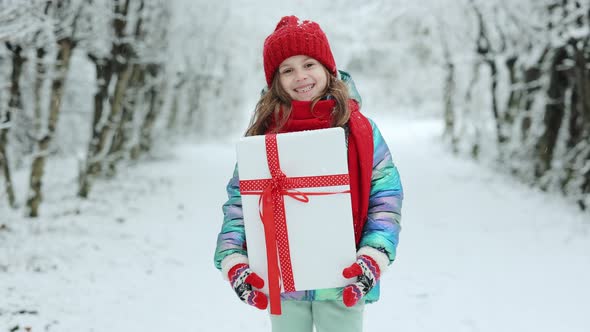 Little Girl With Christmas Box Gift in Winter Outdoors on Xmas Day