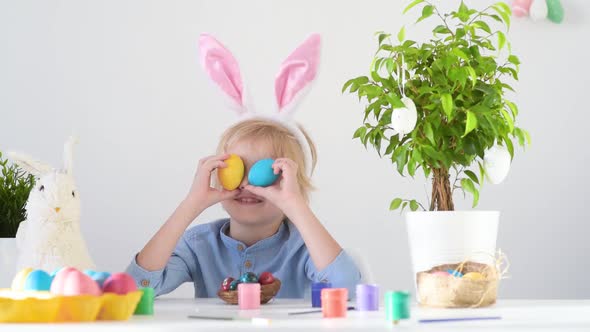 Cute boy having fun with colored eggs for Easter holiday