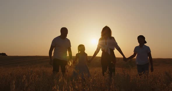 Happy Family With Children In The Field At Sunset