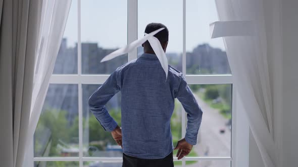 Back View of Stressed African American Man Throwing Out Paperwork Sighing Looking Out the Window in alt