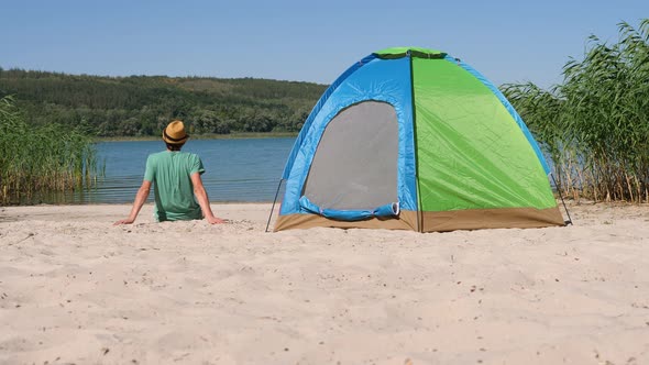 Back View Guy Resting Alone in Camping Tent on Green Eco Travel alt