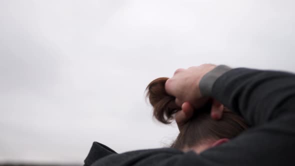 A Man with a Beard Ties His Hair in a Ponytail Collects with His Hands