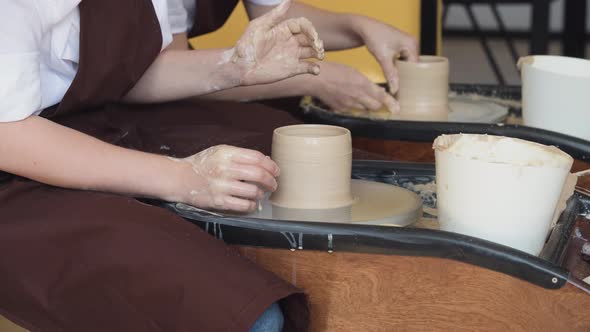 Two Women Make Pottery on a Pottery Wheels, Shaping Clay By Their Hands, Close Up. Pottery Craft alt