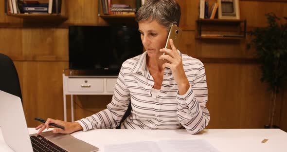Business woman taking on mobile phone while using laptop  alt