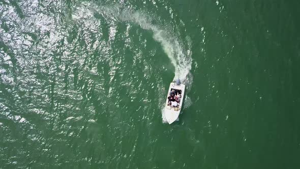 Aerial Top Down Tracking shot of motor boat speeding away in a circle alt