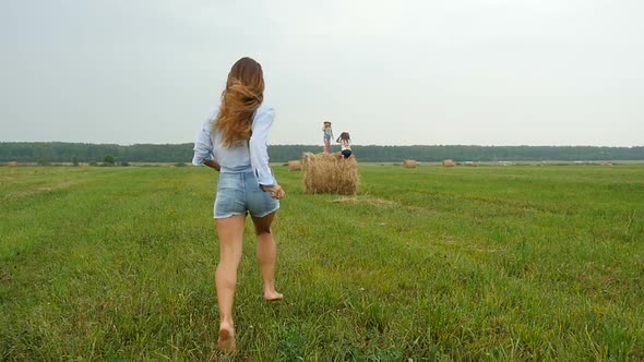 Mum Runs on the Field to her Kids Sitting on Haystack