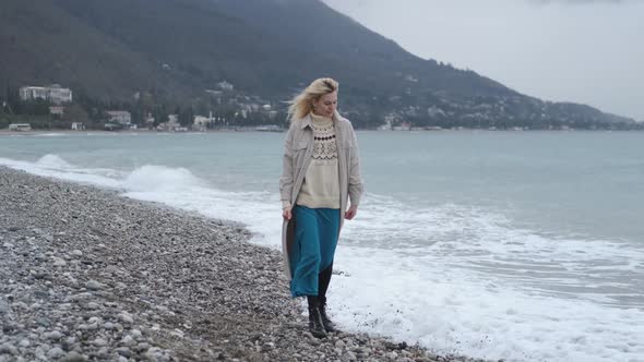 Scandinavian woman walks on a rocky beach in bad weather