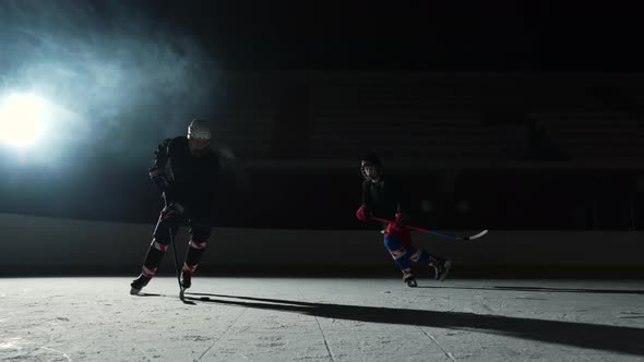 Two Sportsmen Hockey Players Who are Sliding on Ice Arena and Dribbles Hitting Puck with Stick alt