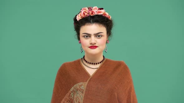 Fashion Portrait of Woman with Flowers in Hair As Frida Kahlo Posing on Camera with Playful Look alt