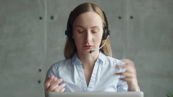 Happy Female Manager Wearing Wireless Headphones, Looking at Laptop Screen, Holding Pleasant alt