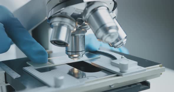 Close Up Shot of the Scientist Studies Examining of Test Sample Under the Microscope. alt