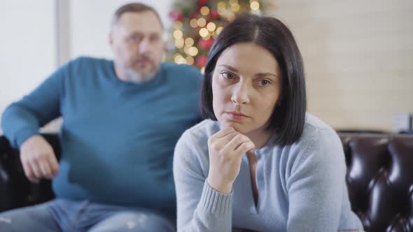 Portrait of Frustrated Caucasian Brunette Woman Sitting on Couch on Christmas Eve and Thinking As alt