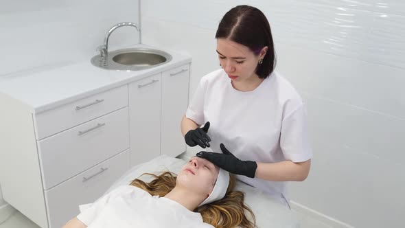 Cosmetologist Applies a Woman a Therapeutic Mask on Her Face alt