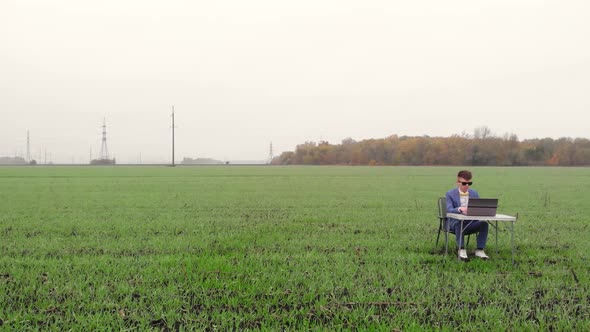 Around Drone Fly View of Young Man Working Remotely with Laptop Outside Alone Isolated on Spring alt