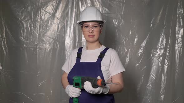 Woman Builder in Blue Overalls and White Hard Hat Helmet with Puncher