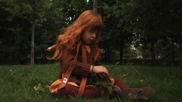 Toddler Girl with Down Syndrome Sitting on the Grass in Park and Playing