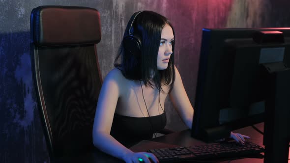 Serious Woman Gamer Playing Online Game on a Pc Computer Wearing Headset and Talking with a Team alt