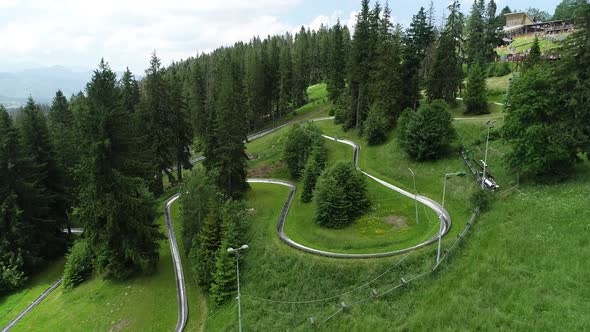Aerial view of bobsleigh track on green mountain hill. Downhill with summer bobsleigh.