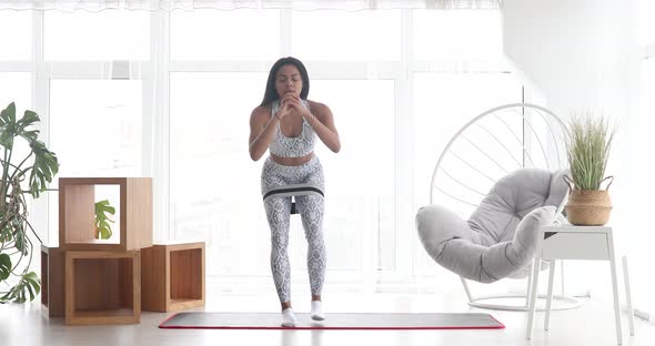 Sporty black woman is training at home in living room.