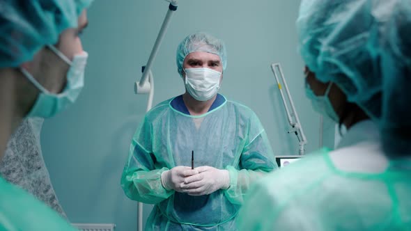 Surgeon Having a Talk with People Wearing Protective Masks and Gowns