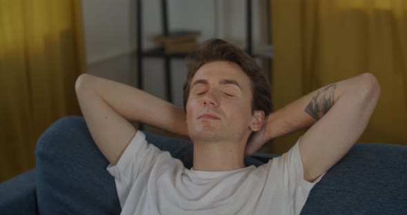 Young Man Relaxing on Sofa with Closed Eyes Close Up Slow Motion. Handheld Portrait of Person alt