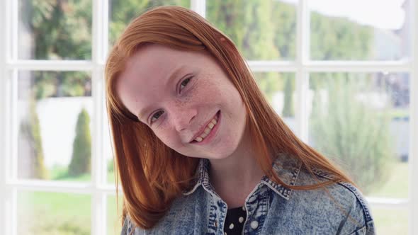 Funny Face of Teen Redhead Girl with Freckles Against White Window