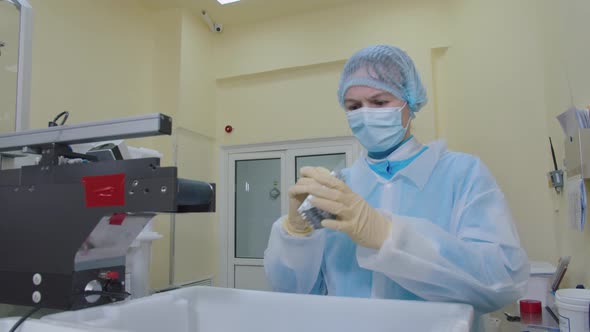 Pharma Worker in Protective Mask and Medical Uniform Examines and Checks the Packaged Pills Falling