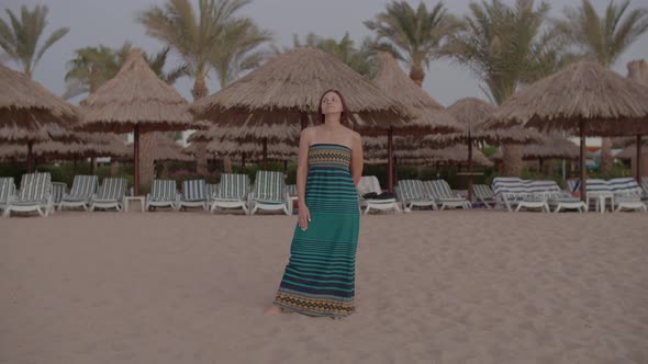 30s Woman in Dress Standing Barefoot Alone on Empty Beach Waiting for Sunrise alt