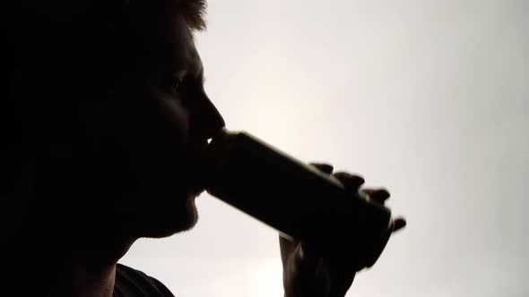 The Silhouette of Male head drinking from a aluminum can