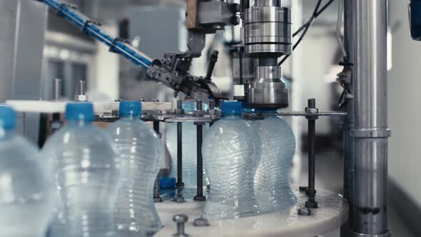 Water Factory Industrial Machine Puts Caps on Plastic PET Bottles with Water Close Up