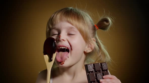 Joyful Smiling Child Kid Girl with Dirty Face From Melted Chocolate on Dark Background in Studio alt