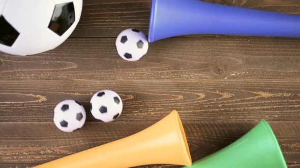 Soccer ball and Vuvuzela stadium horns on a wood background. alt