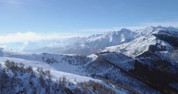 Backward Aerial on White Snow Mountain Peak in Winter Revealing Valley