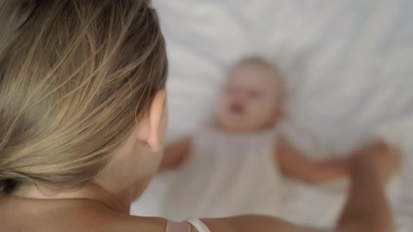 Funny exercises with a baby girl on a bed alt