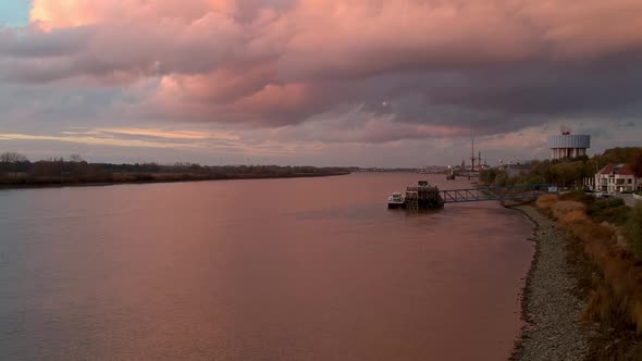 Pan over pink reflecting light off clouds and ships docking station. alt
