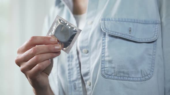 Woman's Hand Putting Condom Package in Her Pocket, Contraception, Close-Up alt