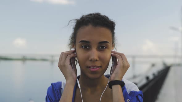 Young Afro-american Woman Is Looking at the Camera and Wearing Headphone for Music Motivation for alt