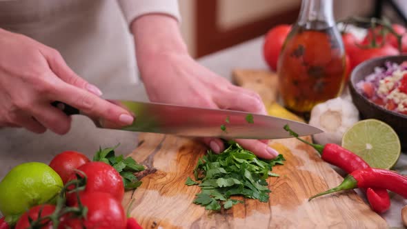 Woman Cutting and Chopping Cilantro or Parsley Greens on a Wooden Board alt