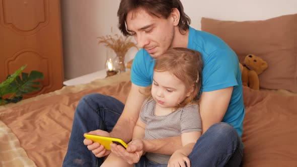 Father and Daughter Watch Cartoon on Phone Home Interior Training