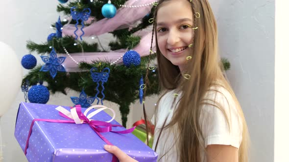 Little Girl of Turkish Appearance Holding a Christmas Present She Laughs Happily alt