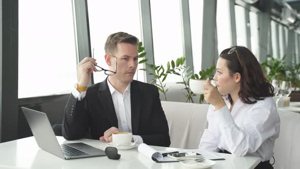Handsome Caucasian Businessman in Spectacles Sit Having Conversation with Colleague