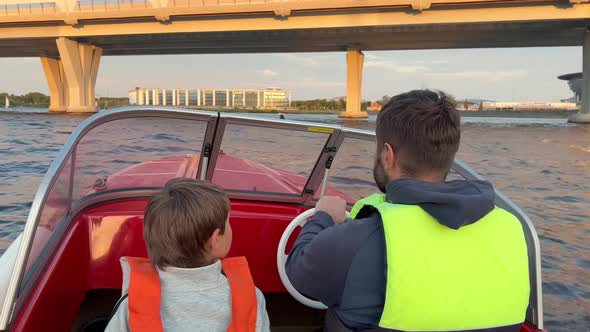 Father and Son Riding Motor Boat Wearing Safety Vests Having a Ride in Neva River Saint Petersburg