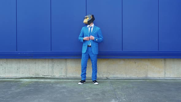 Businessman wearing monkey mask dancing in front of blue wall