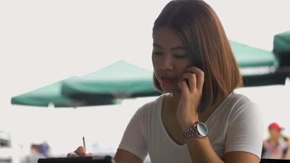 Young Asian woman creative designer using a tablet in coffee shop.