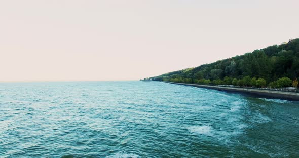 Embankment of the Ocean with Sand and a Road in the Forest at Sunset Shot From a High Point Frame