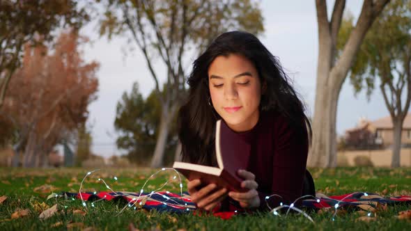 An attractive young woman opening the pages of a book and reading a chapter of the story SLIDE RIGHT alt