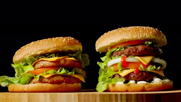 Two Craft Beef Burgers on Wooden Table Isolated on Dark Grayscale Background alt