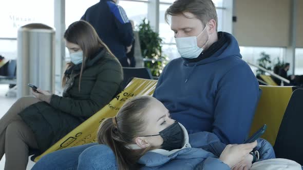 A Young Couple Wearing Masks Sits in an Airport Lounge