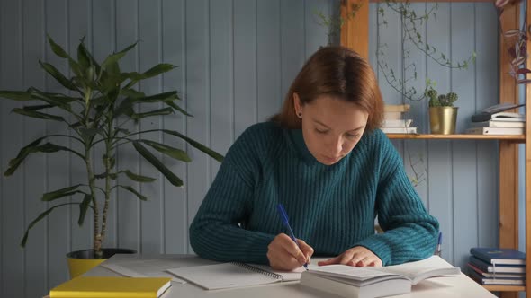 Woman Sitting at Desk Holds Pencil and Writing Essay