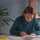 Woman Sitting at Desk Holds Pencil and Writing Essay - VideoHive Item for Sale